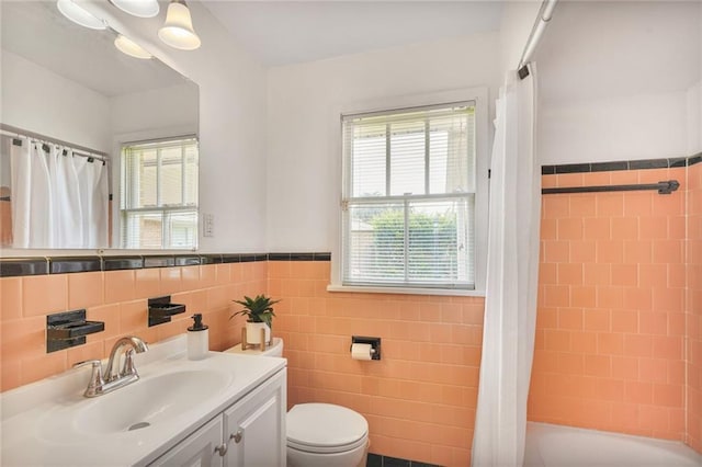 bathroom featuring toilet, shower / bath combo, a wainscoted wall, tile walls, and vanity