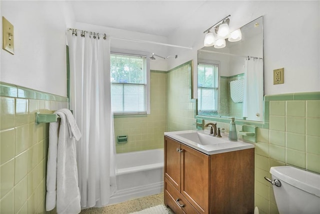 full bathroom featuring tile walls, toilet, vanity, and a wainscoted wall