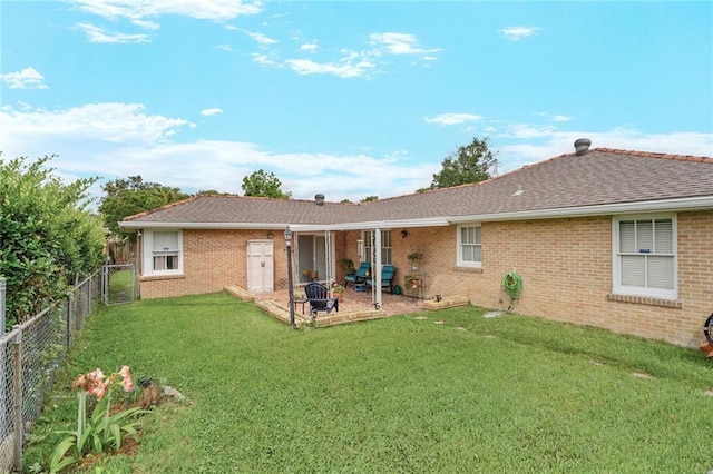 back of house featuring a fenced backyard, brick siding, a patio, and a yard