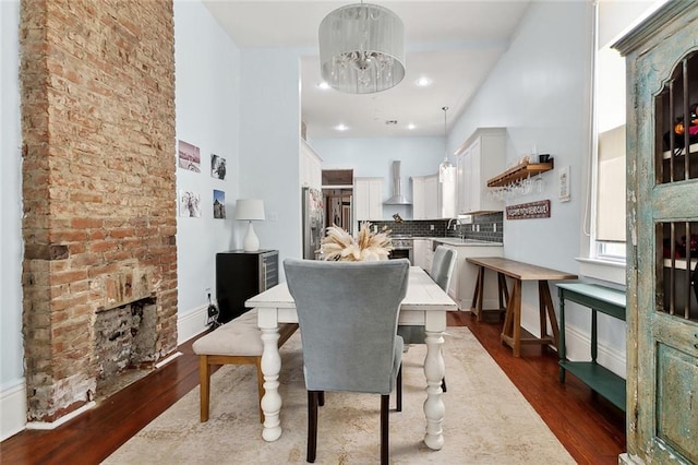 3605 Constance St, New Orleans, LA 70115 - dining room with a notable chandelier, a brick fireplace, a high ceiling, and dark wood-style floors