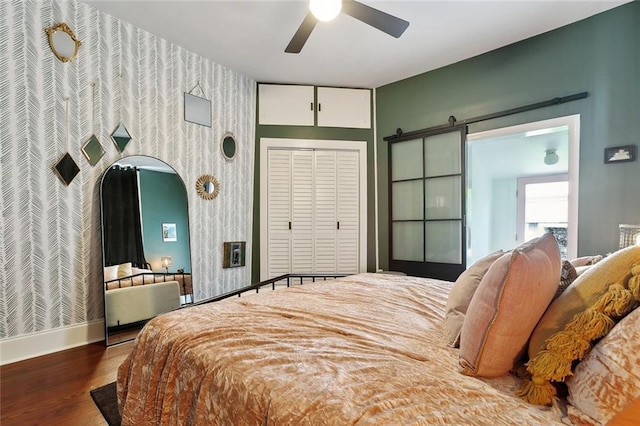 3605 Constance St, New Orleans, LA 70115 - bedroom featuring wood finished floors, a ceiling fan, wallpapered walls, a barn door, and baseboards