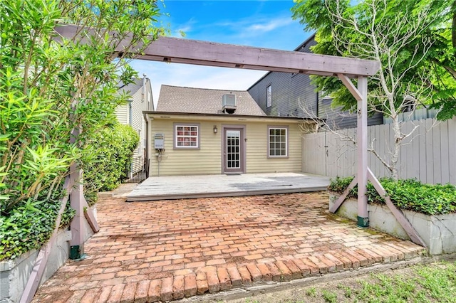 rear view of property featuring a shingled roof, a patio area, fence, and a deck