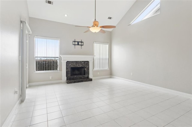 unfurnished living room featuring a ceiling fan, a wealth of natural light, a high end fireplace, and visible vents