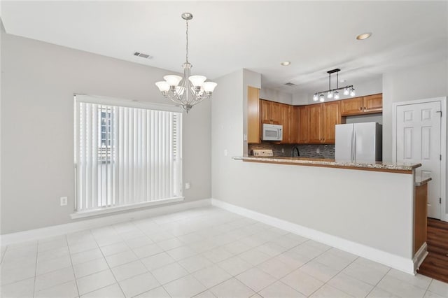kitchen with a notable chandelier, white appliances, hanging light fixtures, a peninsula, and tasteful backsplash