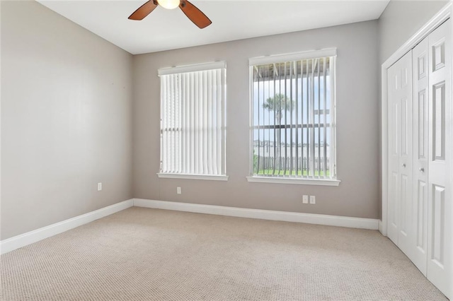 unfurnished bedroom featuring baseboards, light carpet, and a closet