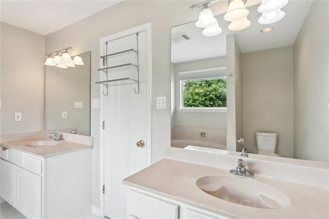 full bath with toilet, a chandelier, two vanities, and a sink