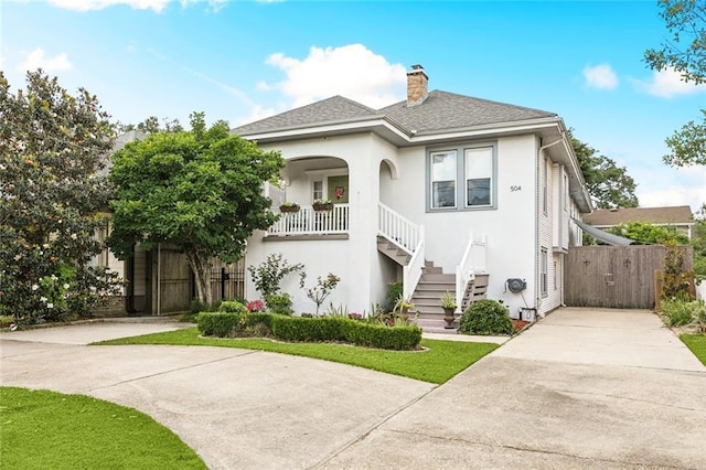 504 N Labarre Rd, Metairie, LA 70001 - view of front of home with fence, concrete driveway, stucco siding, stairway, and a chimney