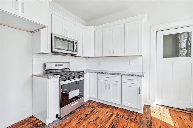 2113 Leonidas St, New Orleans, LA 70118 - kitchen featuring appliances with stainless steel finishes, white cabinetry, light stone countertops, backsplash, and dark wood finished floors