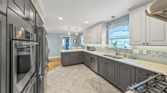 kitchen with a sink, stainless steel appliances, a healthy amount of sunlight, crown molding, and gray cabinets