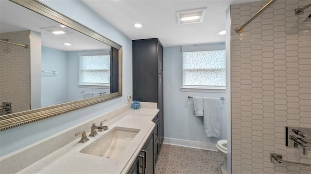 full bathroom featuring a tile shower, baseboards, vanity, and toilet