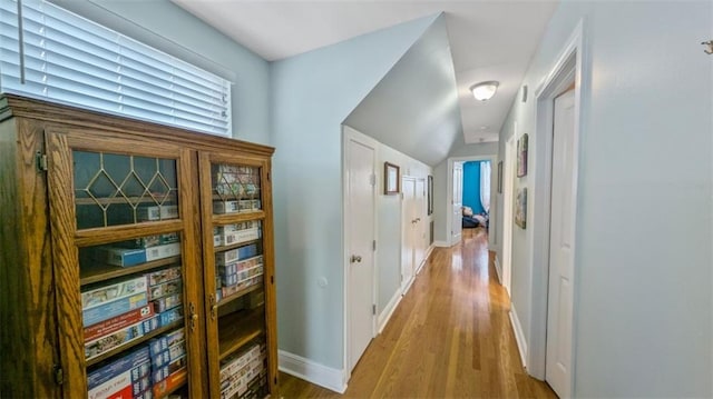 corridor with baseboards and wood finished floors
