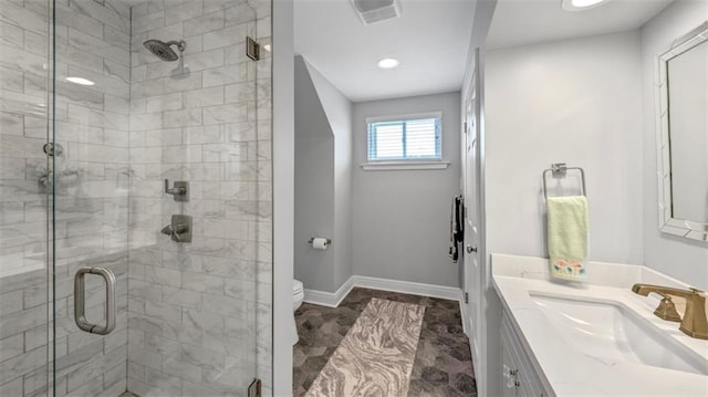 full bath featuring toilet, vanity, visible vents, a shower stall, and baseboards