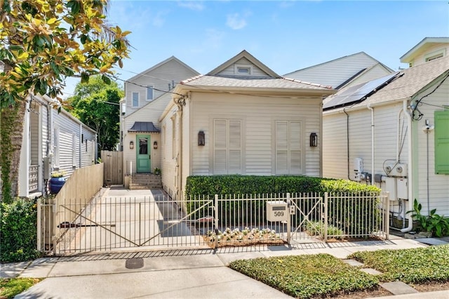shotgun-style home with a fenced front yard and a gate