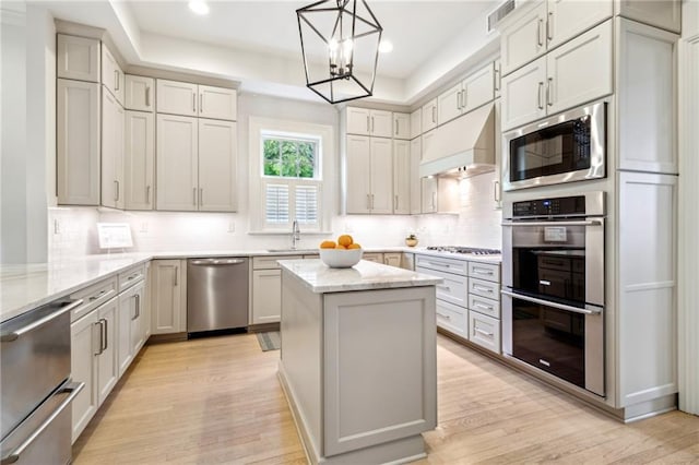 509 Eleonore St, New Orleans, LA 70115 - kitchen featuring appliances with stainless steel finishes, extractor fan, light wood finished floors, a chandelier, and tasteful backsplash