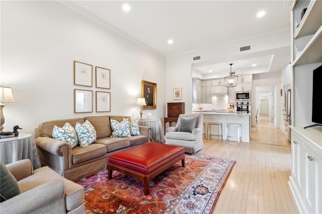 living room with recessed lighting, light wood-style flooring, and ornamental molding