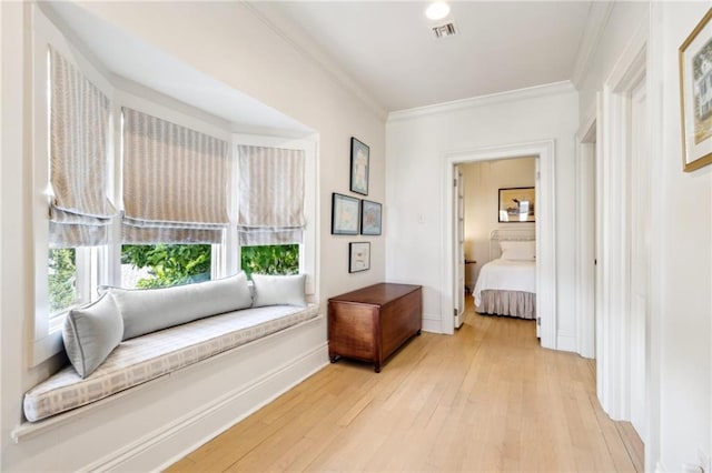 sitting room with light wood-style flooring, crown molding, and baseboards