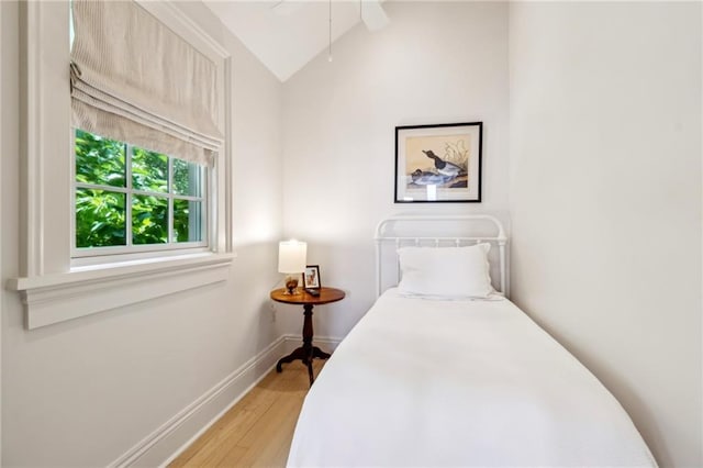 bedroom featuring lofted ceiling, light wood-style floors, baseboards, and ceiling fan