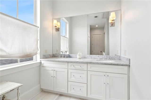 bathroom with double vanity, visible vents, baseboards, and a sink
