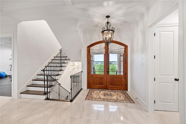 entrance foyer with french doors, a notable chandelier, baseboards, ornamental molding, and stairs