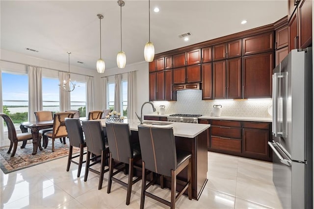 kitchen with a sink, tasteful backsplash, visible vents, light countertops, and high end refrigerator