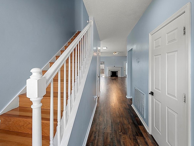 1001 W Chateau Lafitte Dr, Kenner, LA 70065 - hallway featuring stairs, dark wood-style flooring, a textured ceiling, and baseboards