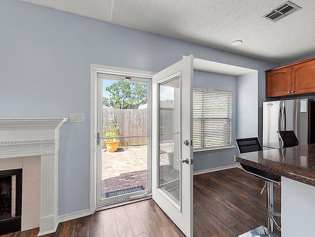 1001 W Chateau Lafitte Dr, Kenner, LA 70065 - entryway featuring plenty of natural light, baseboards, dark wood finished floors, a tiled fireplace, and a textured ceiling