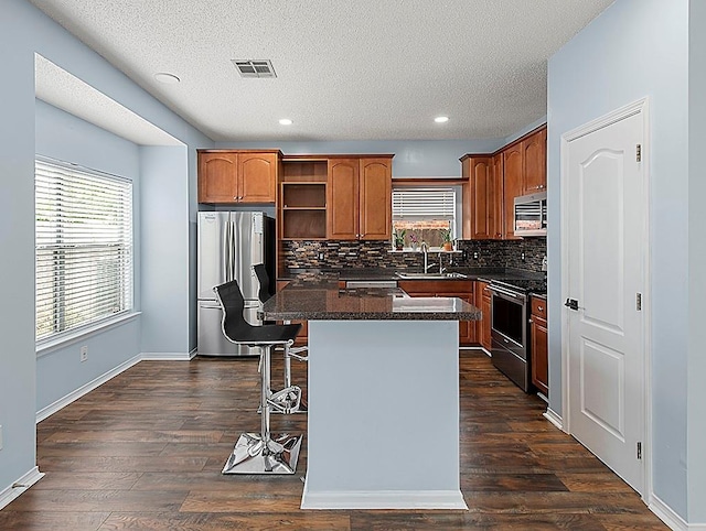 1001 W Chateau Lafitte Dr, Kenner, LA 70065 - kitchen featuring appliances with stainless steel finishes, backsplash, open shelves, a kitchen island, and dark countertops