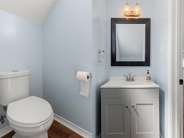 1001 W Chateau Lafitte Dr, Kenner, LA 70065 - bathroom with vanity, baseboards, toilet, a textured ceiling, and wood finished floors