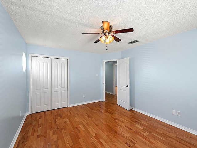 1001 W Chateau Lafitte Dr, Kenner, LA 70065 - unfurnished bedroom featuring wood finished floors, a textured ceiling, baseboards, a closet, and ceiling fan