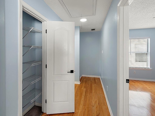 1001 W Chateau Lafitte Dr, Kenner, LA 70065 - hall with attic access, wood finished floors, and baseboards