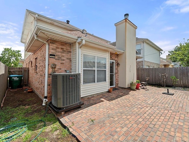 1001 W Chateau Lafitte Dr, Kenner, LA 70065 - rear view of house with central air condition unit, a patio area, a fenced backyard, brick siding, and a chimney