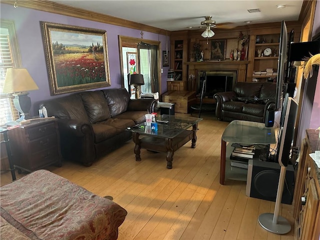 41139 Happywoods Rd, Hammond, LA 70403 - living room with light wood-style flooring, a fireplace, crown molding, visible vents, and ceiling fan