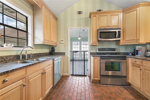 kitchen featuring lofted ceiling, visible vents, appliances with stainless steel finishes, and a sink