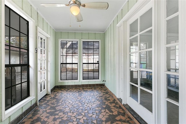 unfurnished sunroom with baseboards, ornamental molding, french doors, and stone finish floor