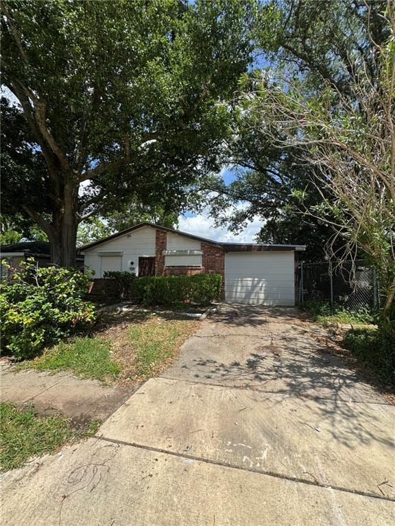 ranch-style house with concrete driveway, fence, and a garage
