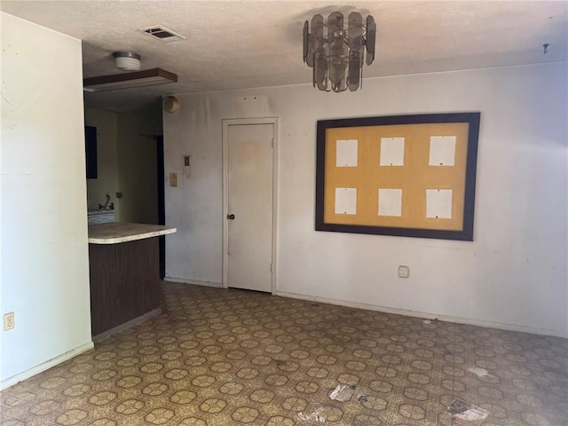 unfurnished room with baseboards, visible vents, and a textured ceiling
