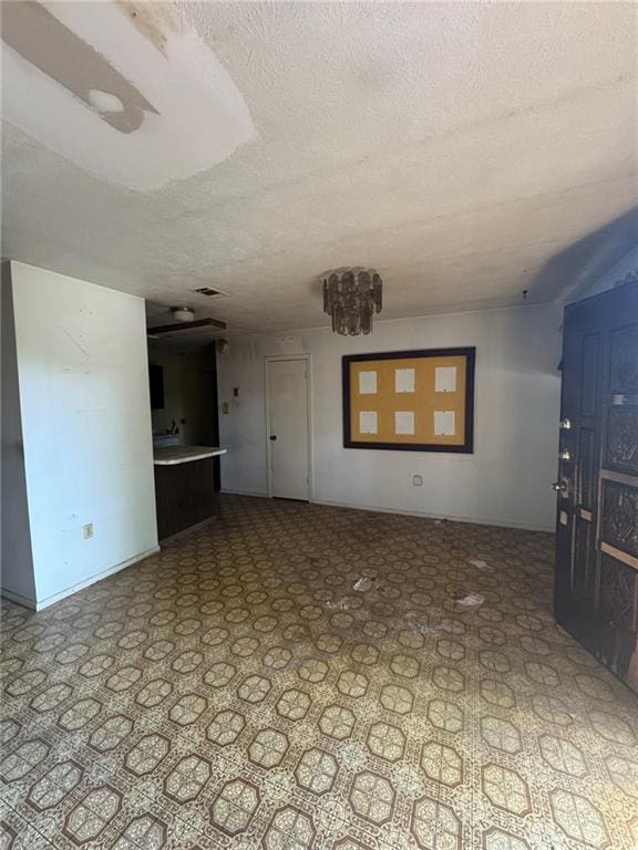 unfurnished living room featuring a textured ceiling and baseboards