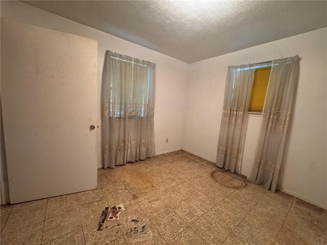empty room with light floors and a textured ceiling