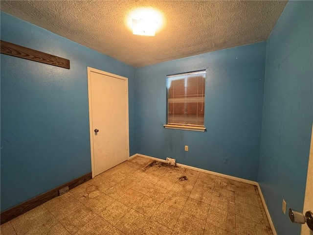 spare room featuring a textured ceiling, baseboards, and tile patterned floors