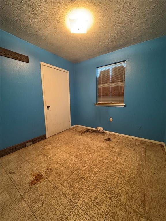 spare room featuring a textured ceiling and baseboards