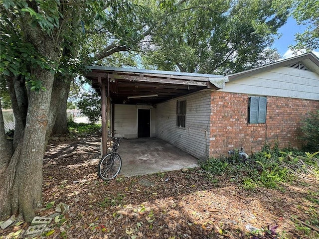 exterior space with a patio, brick siding, and a carport