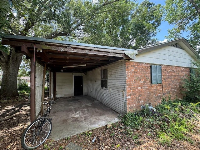 exterior space featuring a patio, brick siding, and an attached carport