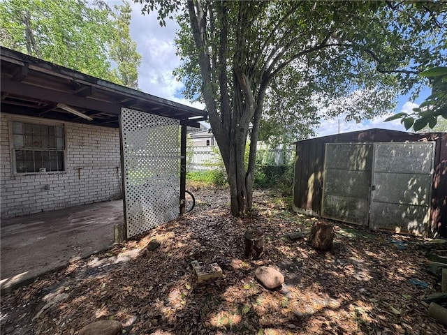 view of yard featuring fence, a shed, and an outbuilding