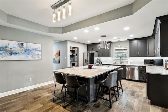 kitchen featuring a center island with sink, light wood finished floors, a breakfast bar area, and appliances with stainless steel finishes