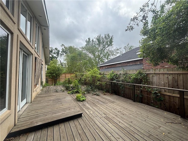wooden terrace with a fenced backyard