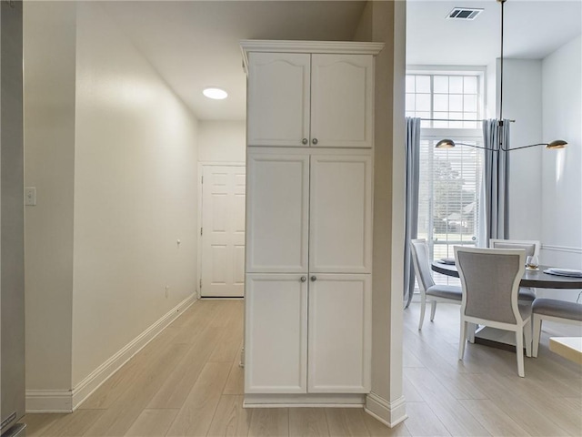 interior space with recessed lighting, baseboards, light wood finished floors, visible vents, and white cabinetry