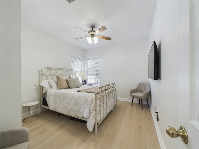 bedroom featuring baseboards, a ceiling fan, visible vents, and light wood-style floors