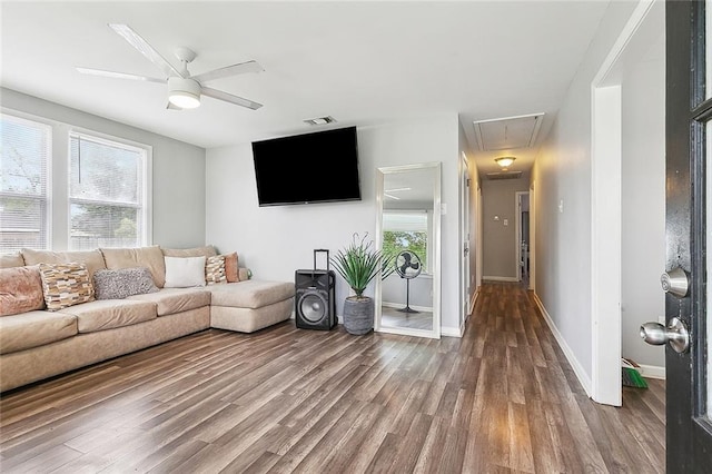 living area with baseboards, ceiling fan, attic access, and wood finished floors