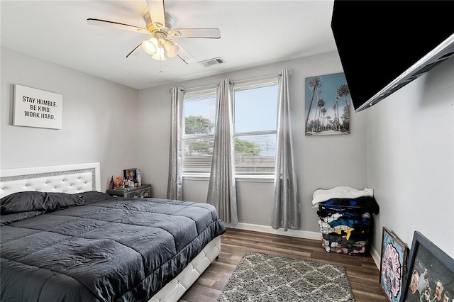 bedroom featuring baseboards, a ceiling fan, visible vents, and wood finished floors