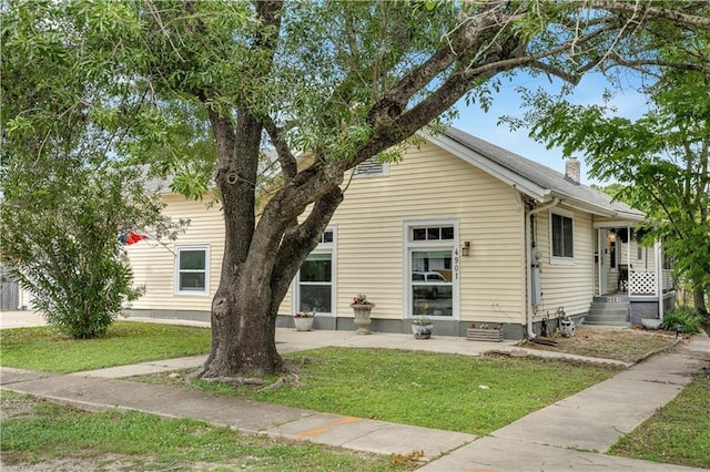view of front of home featuring a front lawn, a chimney, and a patio